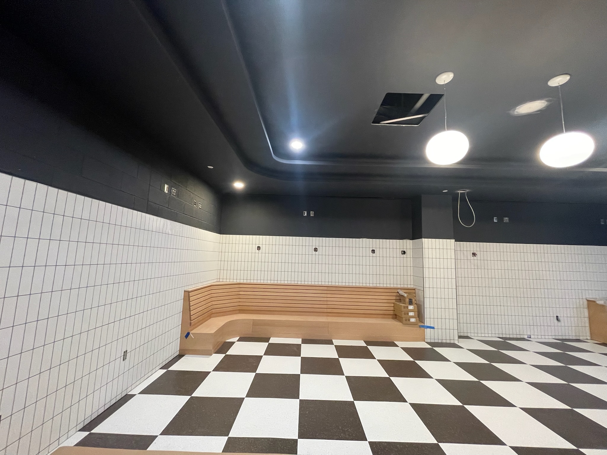Custom millwork bench seating installation at Yankee Stadium with integrated wall paneling and tile backdrop