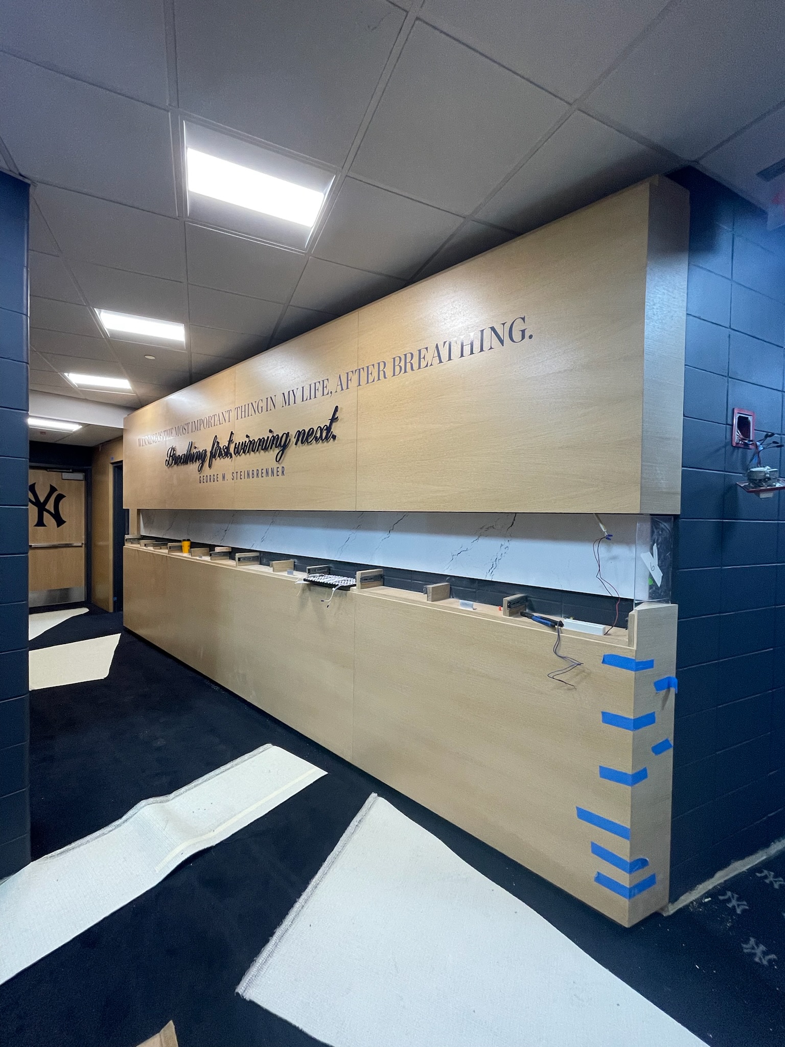 Custom wood wall paneling with engraved signage installation at Yankee Stadium concession area