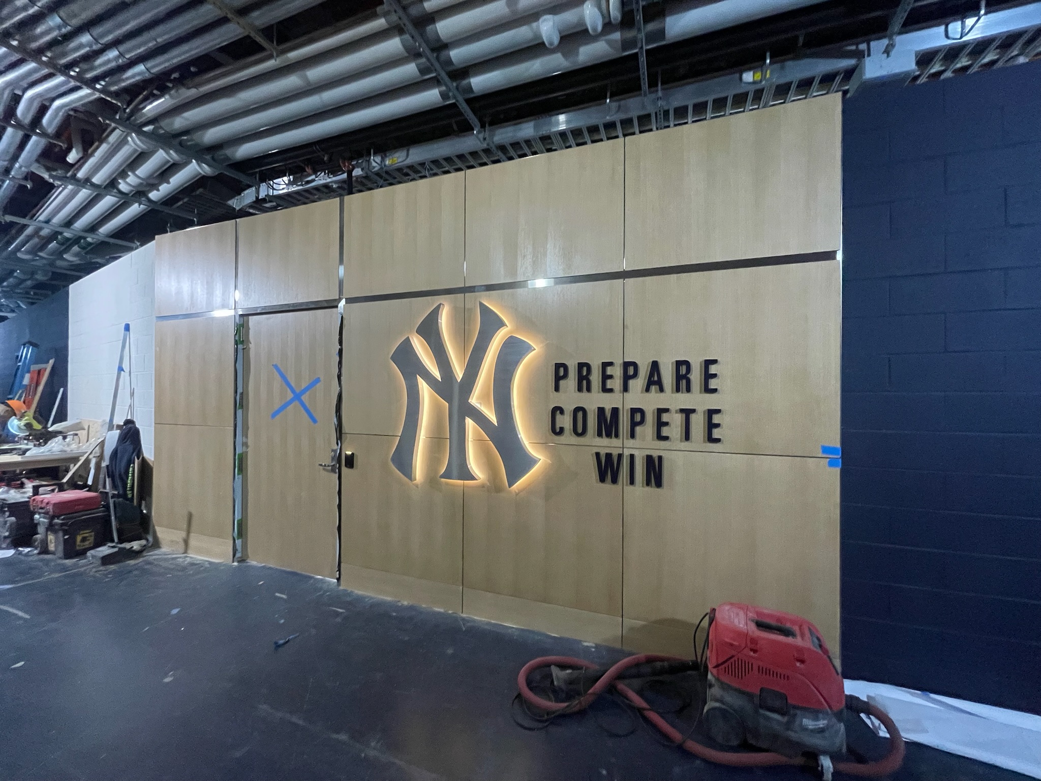 Custom feature wall with illuminated NY logo and wood paneling at Yankee Stadium interior space