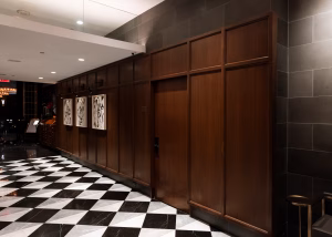 Custom wood wall paneling and architectural millwork at Hotel Belleclaire, featuring warm paneled details, framed artwork, and a black-and-white checkered floor.