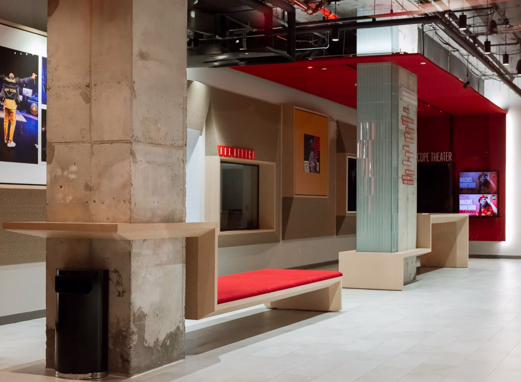 Lobby at the Victoria Theater at the Apollo featuring custom millwork benches, red upholstered seating, display walls, and contemporary architectural details within the historic performance venue
